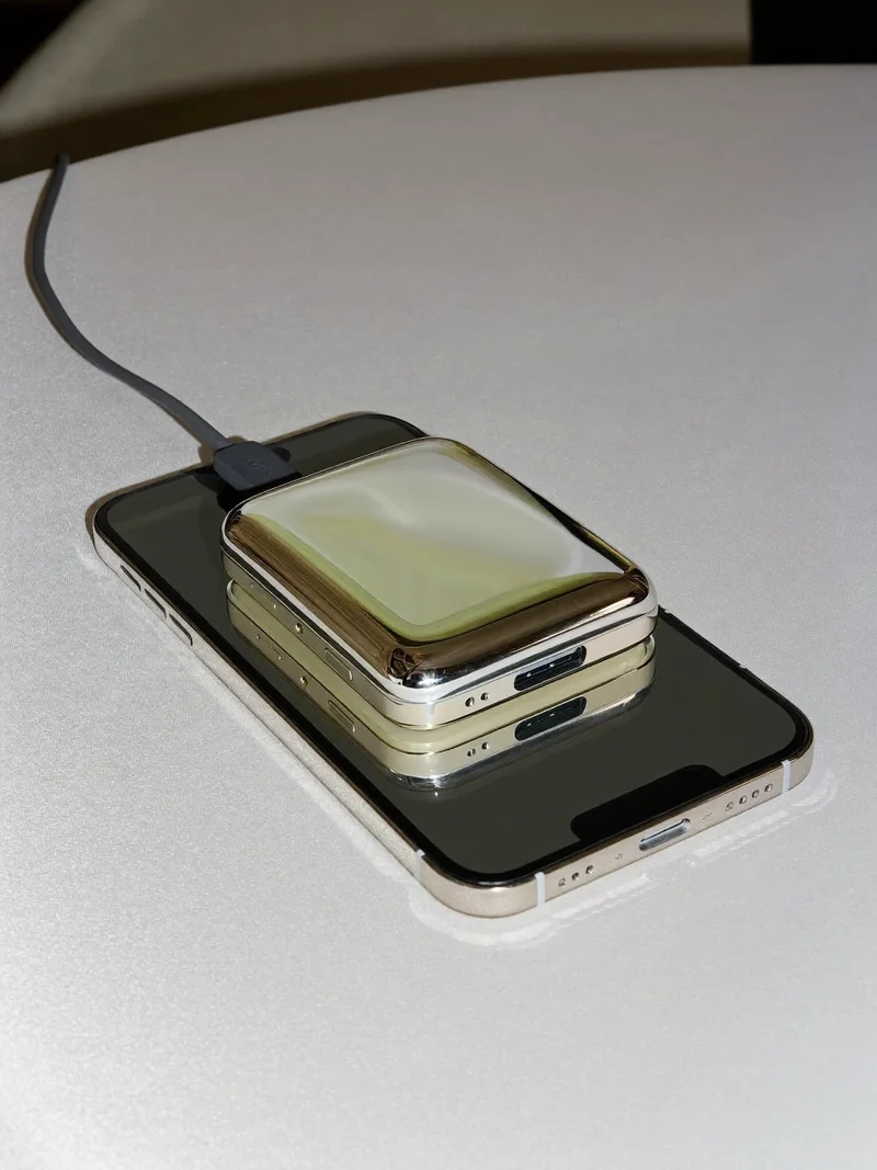Kieszonkowy powerbank połączony krótkim kablem ze smartfonem